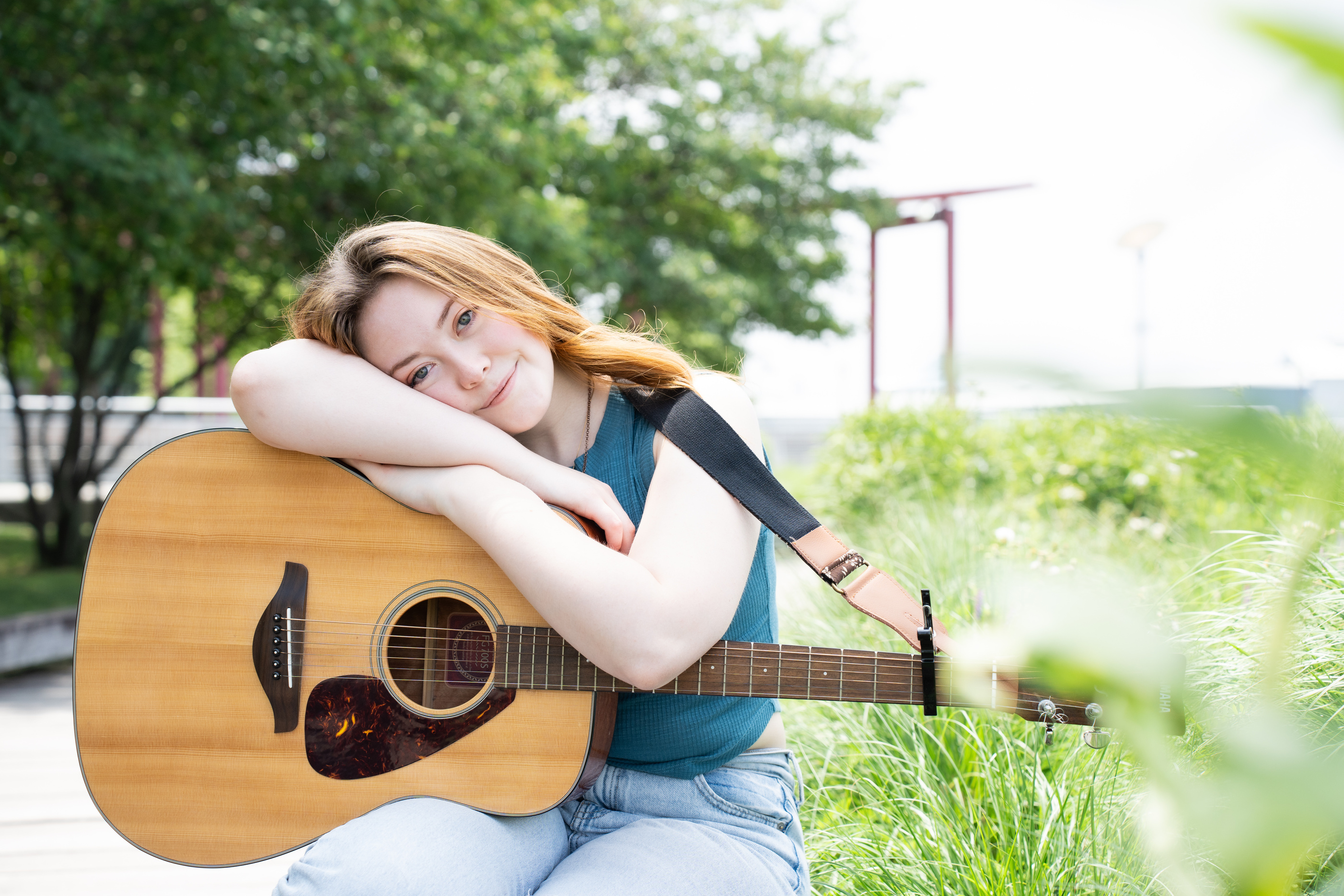 Maddie Ryan sitting on a bench with an acoustic guitar